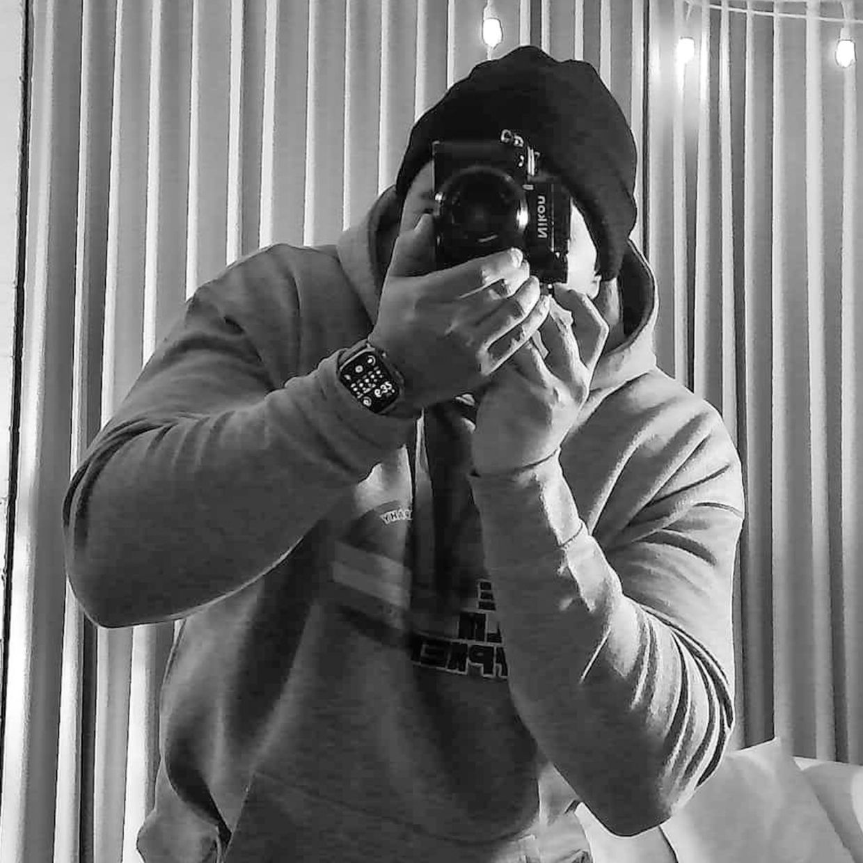 Person in hoodie taking a photo with a camera.
