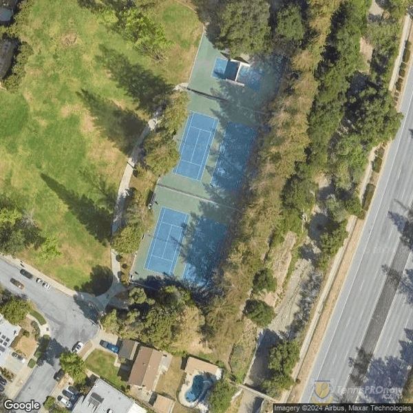Aerial view of tennis courts surrounded by trees and roads.
