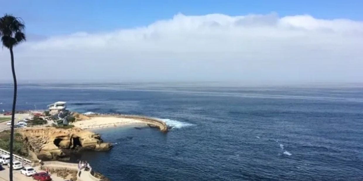 Scenic ocean view with rocky shore and a beach.