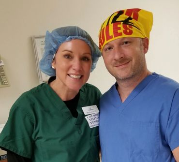 Two medical professionals in scrubs and caps smiling indoors.