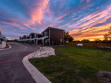 Sunset over modern townhouses with a colorful sky and empty bench.