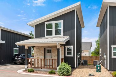 Modern two-story house with black siding and a small porch.