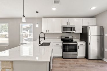 Modern kitchen with white cabinets and stainless steel appliances.