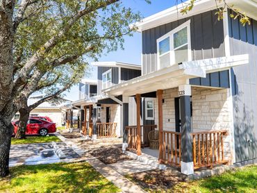 Modern gray and stone townhouses with wooden porches on a sunny day.