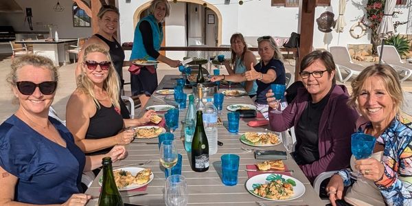 Group of women enjoying a meal together outdoors with drinks and food.