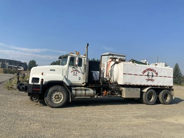 White tanker truck labeled Ironmule parked on gravel under clear sky.