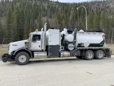 A large white industrial vacuum truck parked on a road.