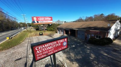 Champion Tire & Automotive shop with signage and a nearby billboard.