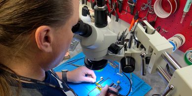 Technician soldering with microscope, repairing electronics