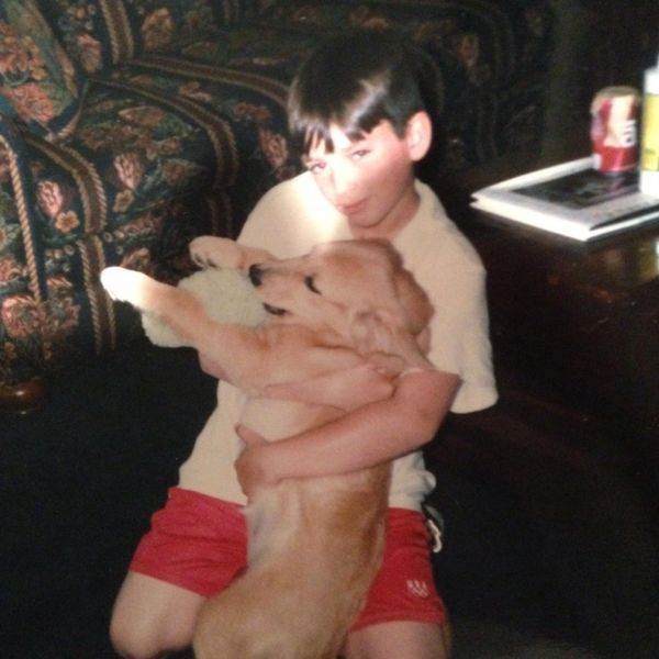 A young boy hugging a golden retriever puppy indoors.