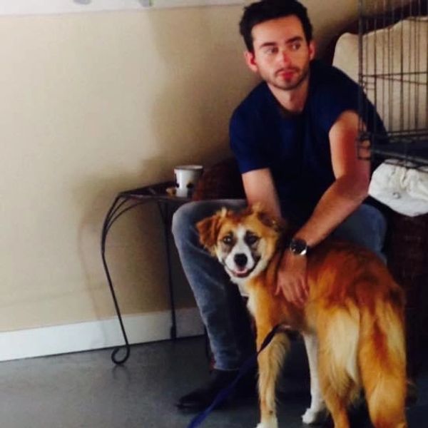 A man sitting indoors petting a happy dog.