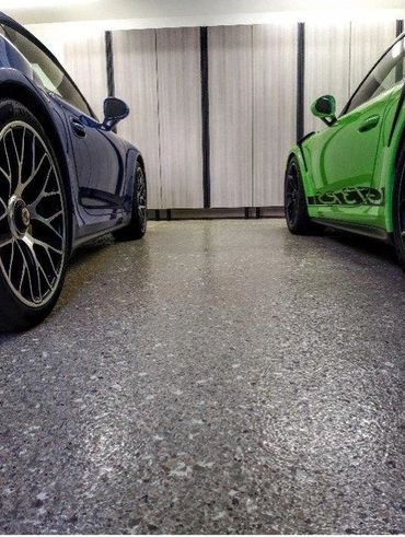 Two sports cars, one blue and one green, parked facing each other indoors.