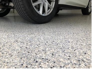 Close-up of a car tire on a speckled garage floor.