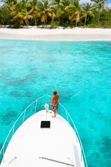 Hombre en barco, mirando costa del Caribe.