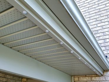 Close-up of a house eavestrough and soffit with small white caps.
