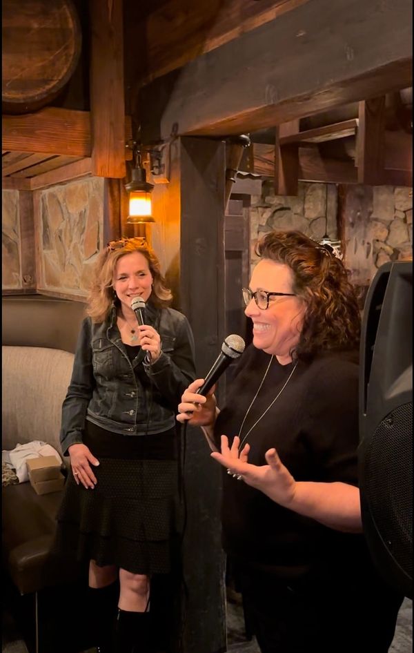 Sarah Paige holding a microphone while speaking in front of a semi-private or group reading.