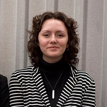 Woman with curly hair in a striped blazer.