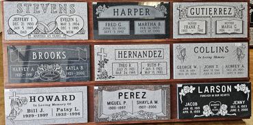 A collection of nine engraved gravestones with family names and dates.