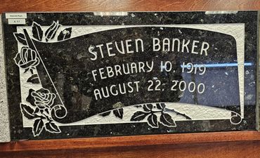 Engraved memorial plaque for Steven Banker with floral designs.