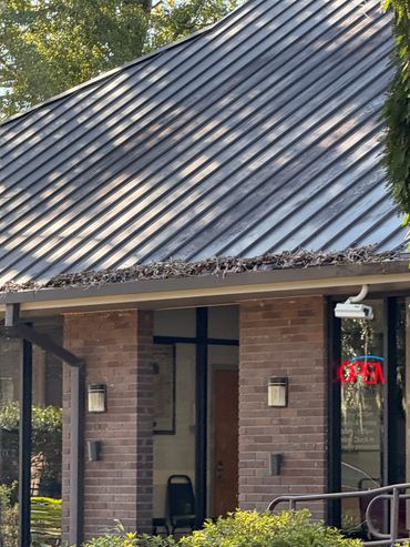 Building entrance with brick walls and a metal roof showing an open sign.