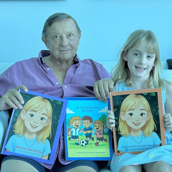 An older man and young girl holding illustrated books, sitting on a couch.