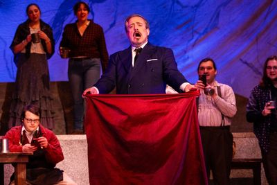 Man performing on stage holding a red cloth.