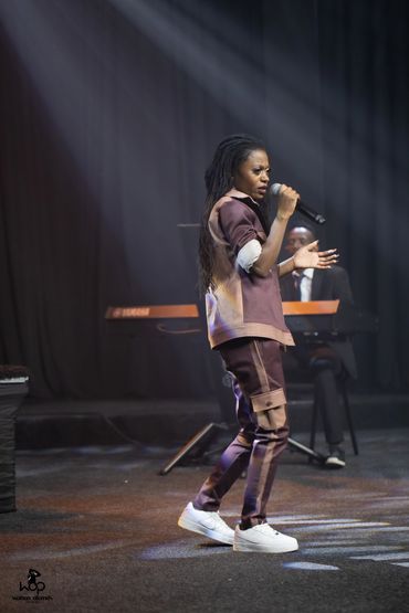 Denise Moyo, poet, singer and songwriter who was born in Zimbabwe singing on stage.