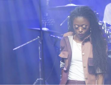 Denise Moyo, poet, singer and songwriter who was born in Zimbabwe singing on stage.