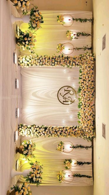 Elegant floral wedding backdrop with soft lighting and monogram.