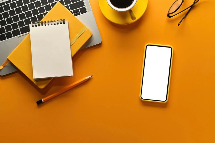 Stack of books next to pencils in a holder and a camera.