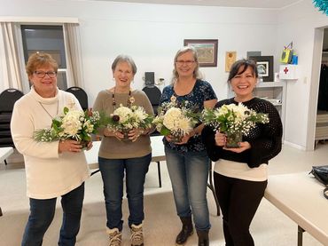 Four women displaying light green flower arrangements at Holiday arrangement workshop in Chase, BC