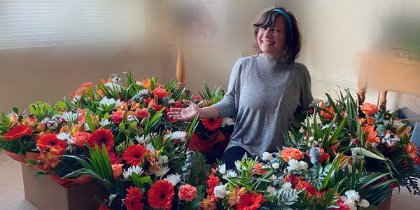 A florist proudly smiling showing off flower arrangements for event