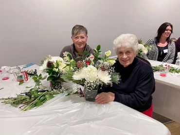 Senior woman creating flower arrangement at therapeutic hands-on flower workshop Kamloops.