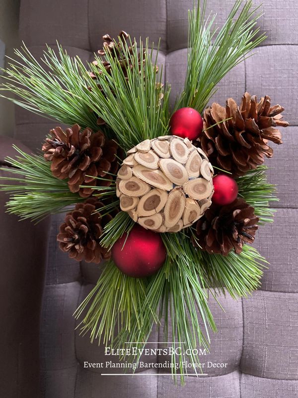 Festive holiday centre piece with evergreens, pinecones and pops of crimson red.