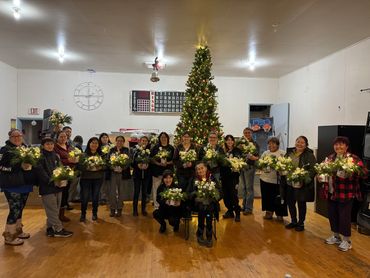 Large indigenous community group at a Christmas arrangement workshop, holding their finished bouquet