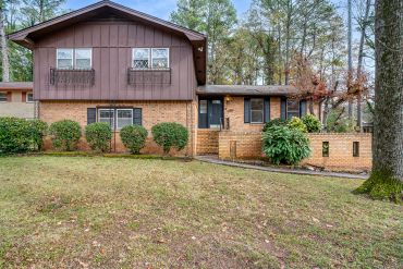 Two-story brick house with brown upper siding and black shutters.