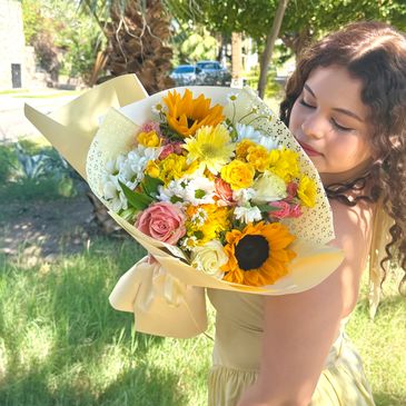 A woman holding a colorful bouquet of flowers outdoors.