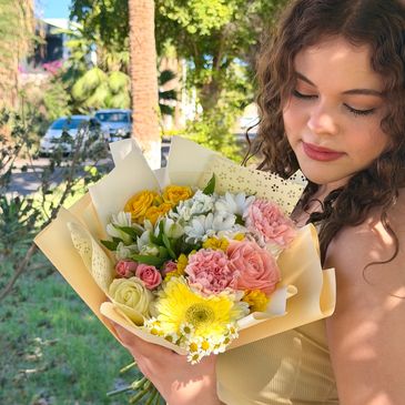 Young woman admiring a colorful bouquet of flowers outdoors.