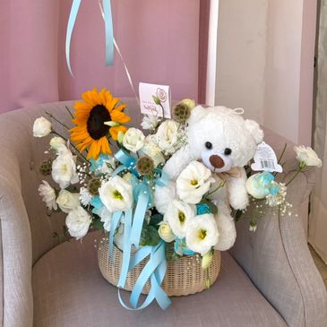 Arreglo floral con oso de peluche y girasol.