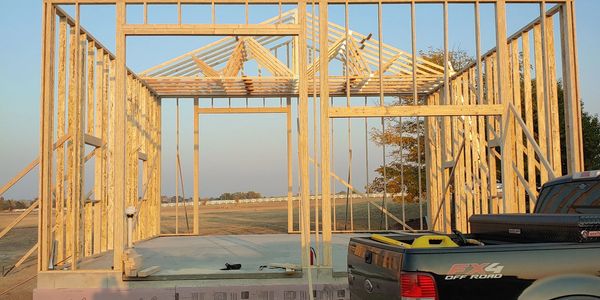 Wooden house frame under construction with a black pickup truck nearby Berthoud CO Carter Lake
