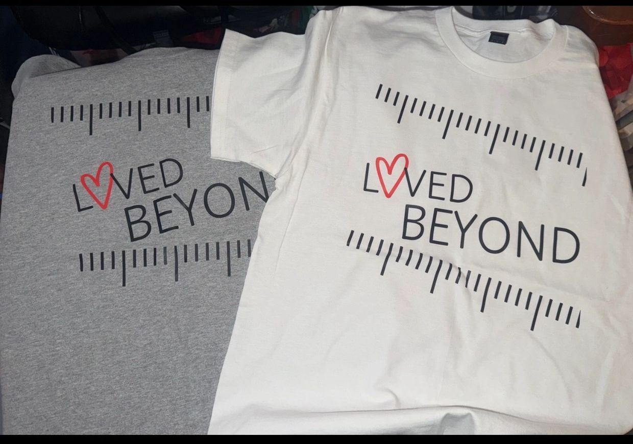 Two t-shirts with the phrase 'Loved Beyond' and a red heart replacing the 'O'.