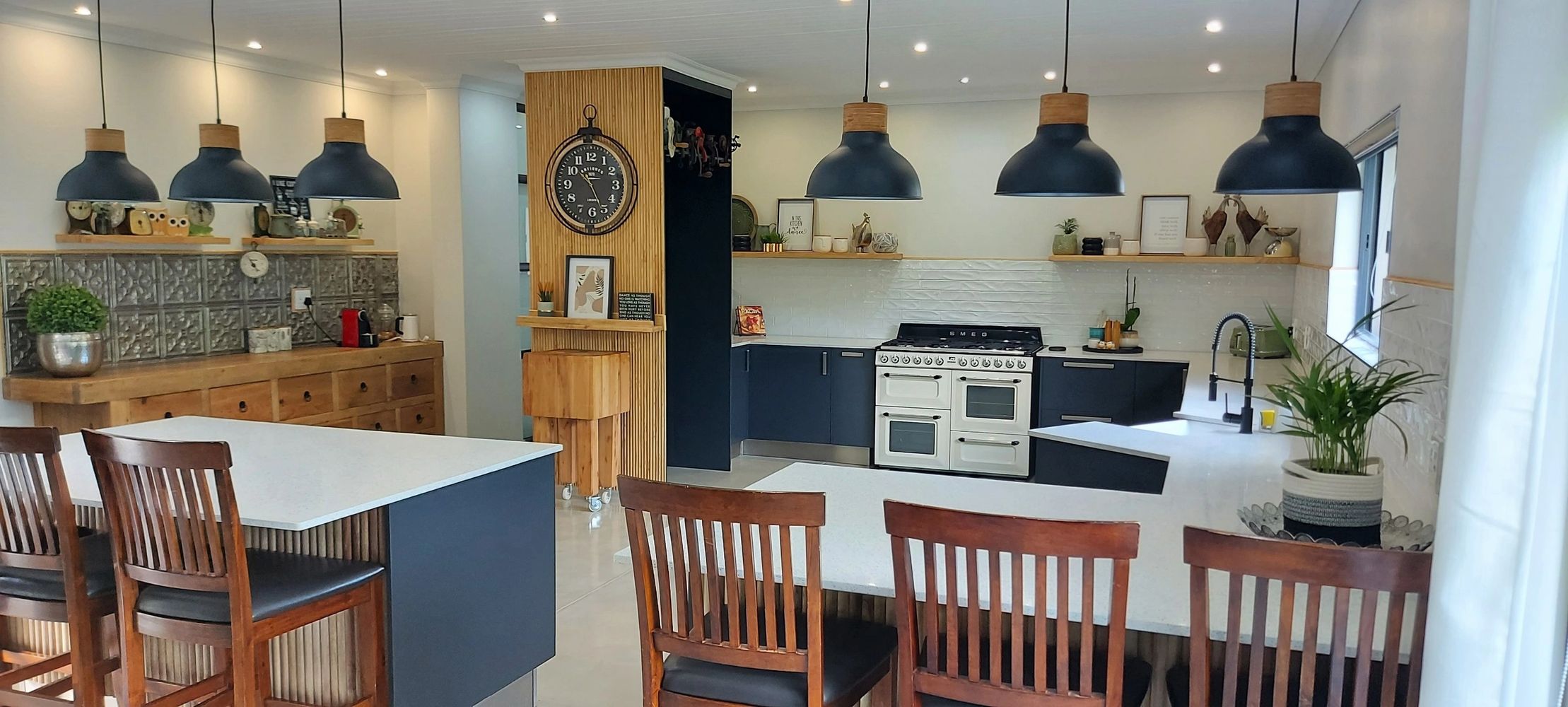 Modern kitchen with wooden accents, black cabinets, and pendant lights.