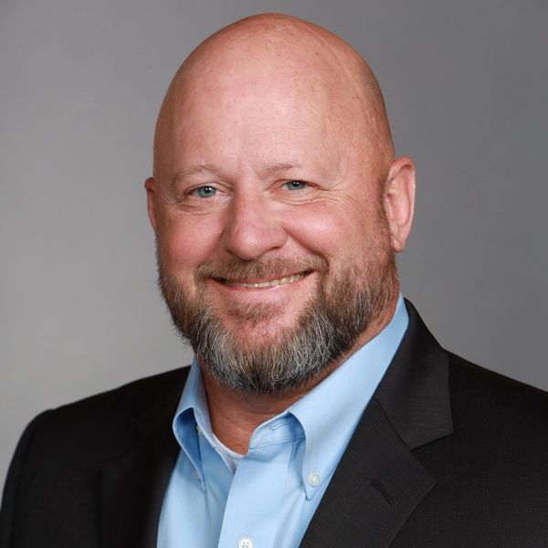 Smiling bald man with beard in business attire.