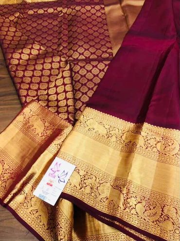 Traditional maroon and gold silk saree with intricate floral and elephant motifs.