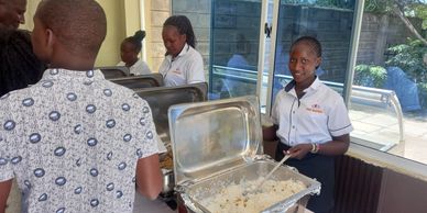 A woman serving rice from a buffet at an indoor event.