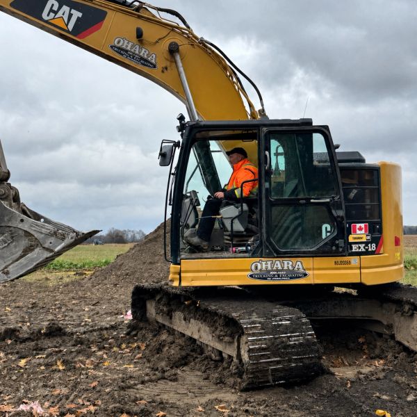A construction worker operates a CAT excavator on a cloudy day.