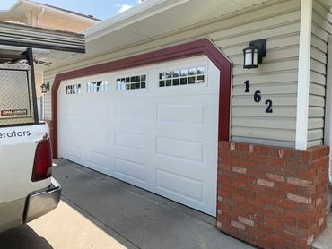 White garage door with red trim and house number 162 on beige siding.