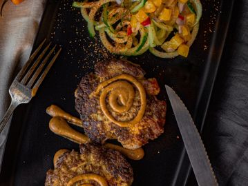 Grilled meat with sauce and vegetable salad.