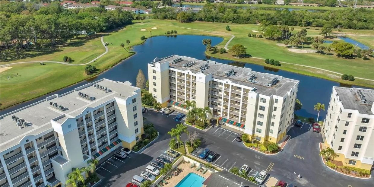A bird's-eye view of residential buildings near a golf course and water body.