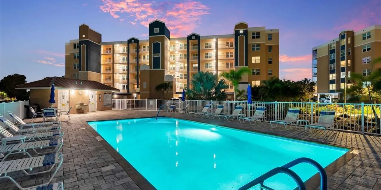 Illuminated outdoor swimming pool with lounge chairs at sunset.